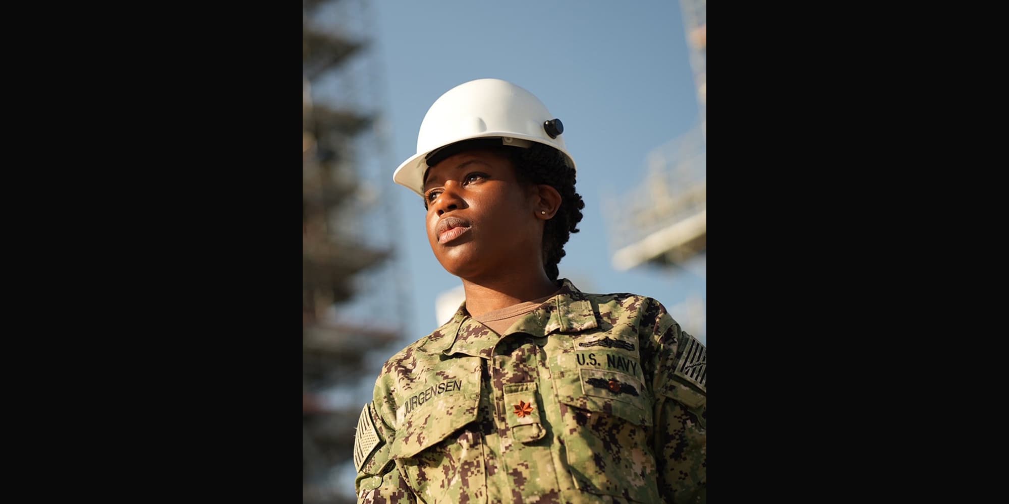 Female Sailor in hard hat gazes toward the horizon. Navy career training builds skills for tomorrow.