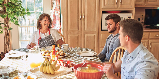 Family members sitting around a table, enjoying a meal together at a joyful gathering.